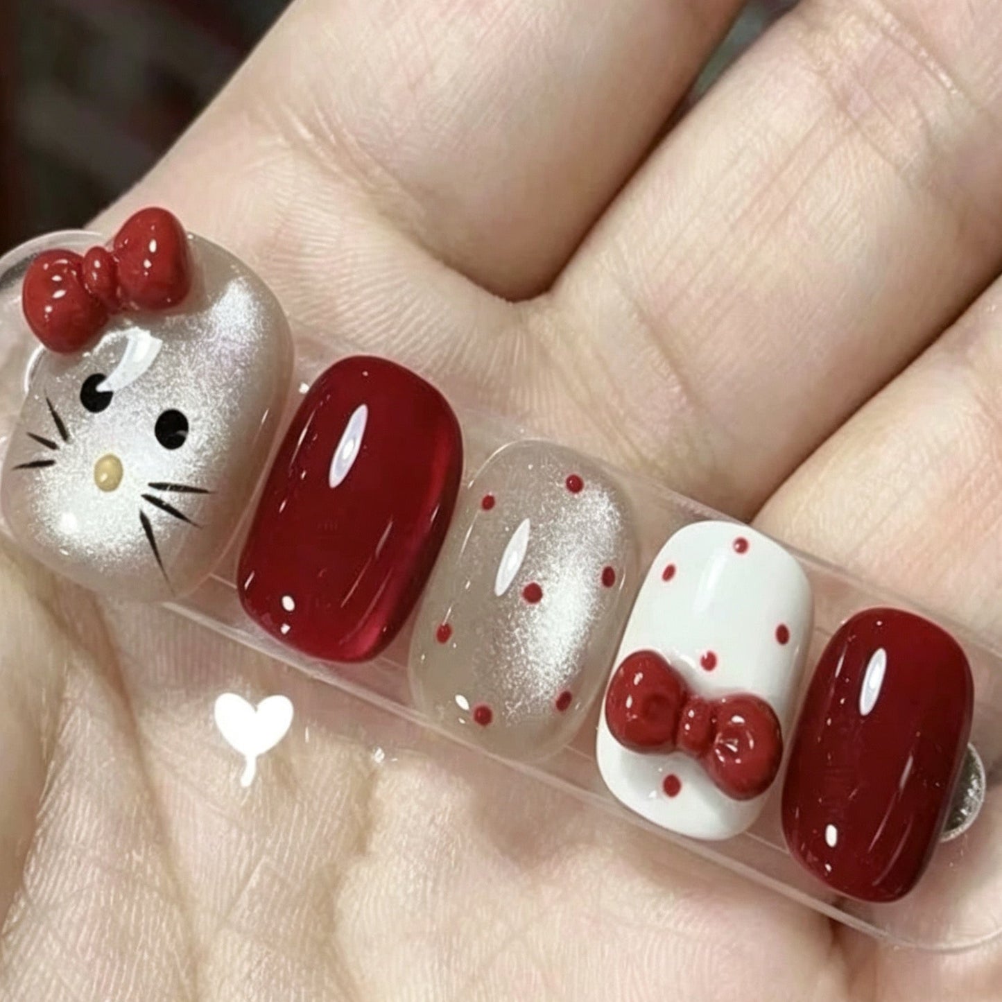 Press-on nails featuring polka dots, cat-eye effect, and bow accents.