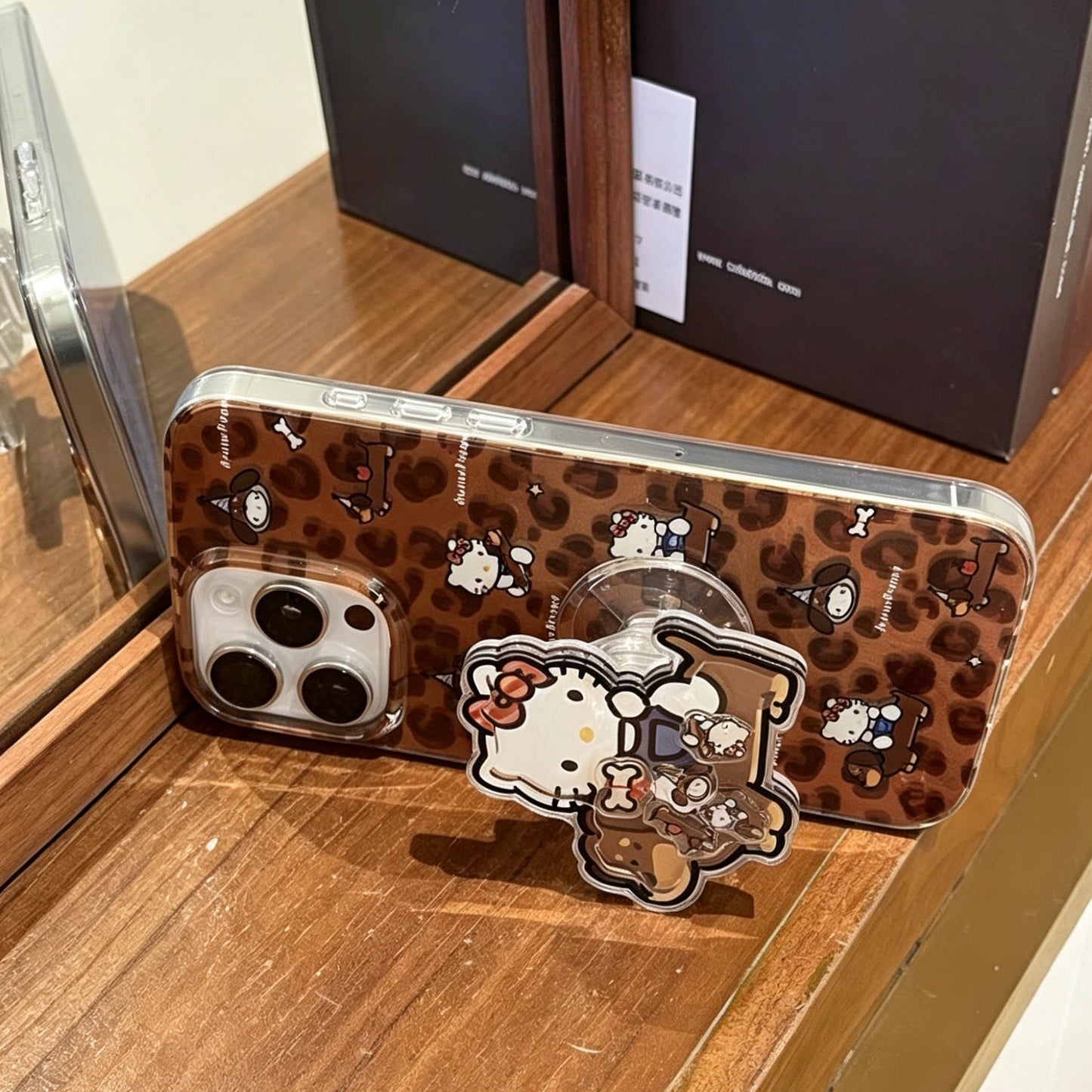 Brown leopard-print phone case featuring a dachshund and Hello Kitty, with a built-in stand.