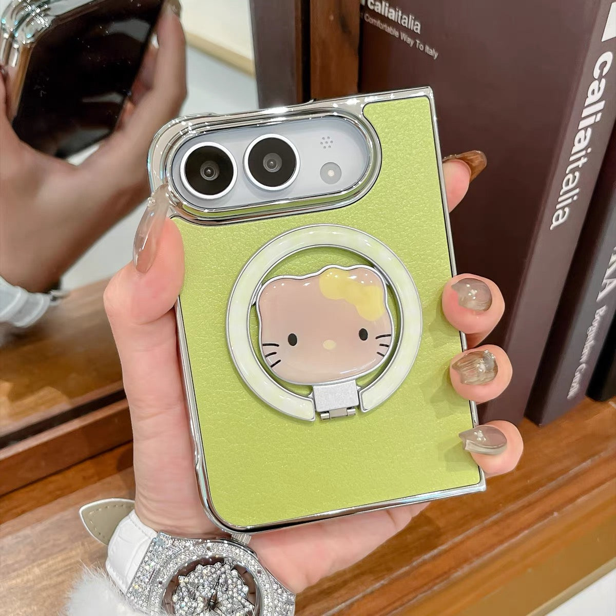 Minimalist solid-color leather-style folding phone case for iPhone Duo featuring a magnetic stand and a cartoon Hello Kitty design.